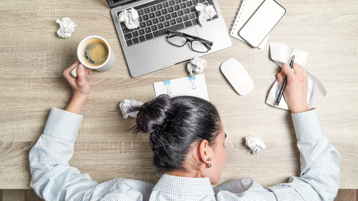 A woman slumped on her desk feeling tired and low energy