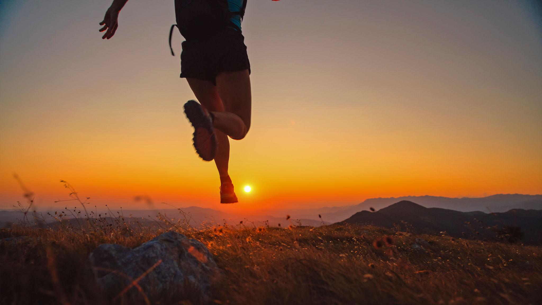 A person running towards the sunset